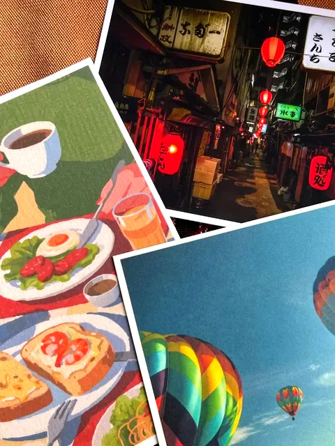Three art print postcards of a cafe meal, a lantern-lit alley, and hot air balloons.