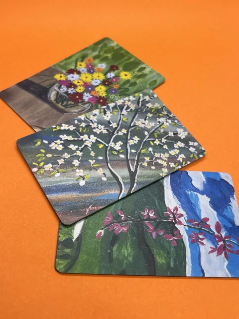 Three custom fridge magnets printed with flower and tree paintings, on orange paper