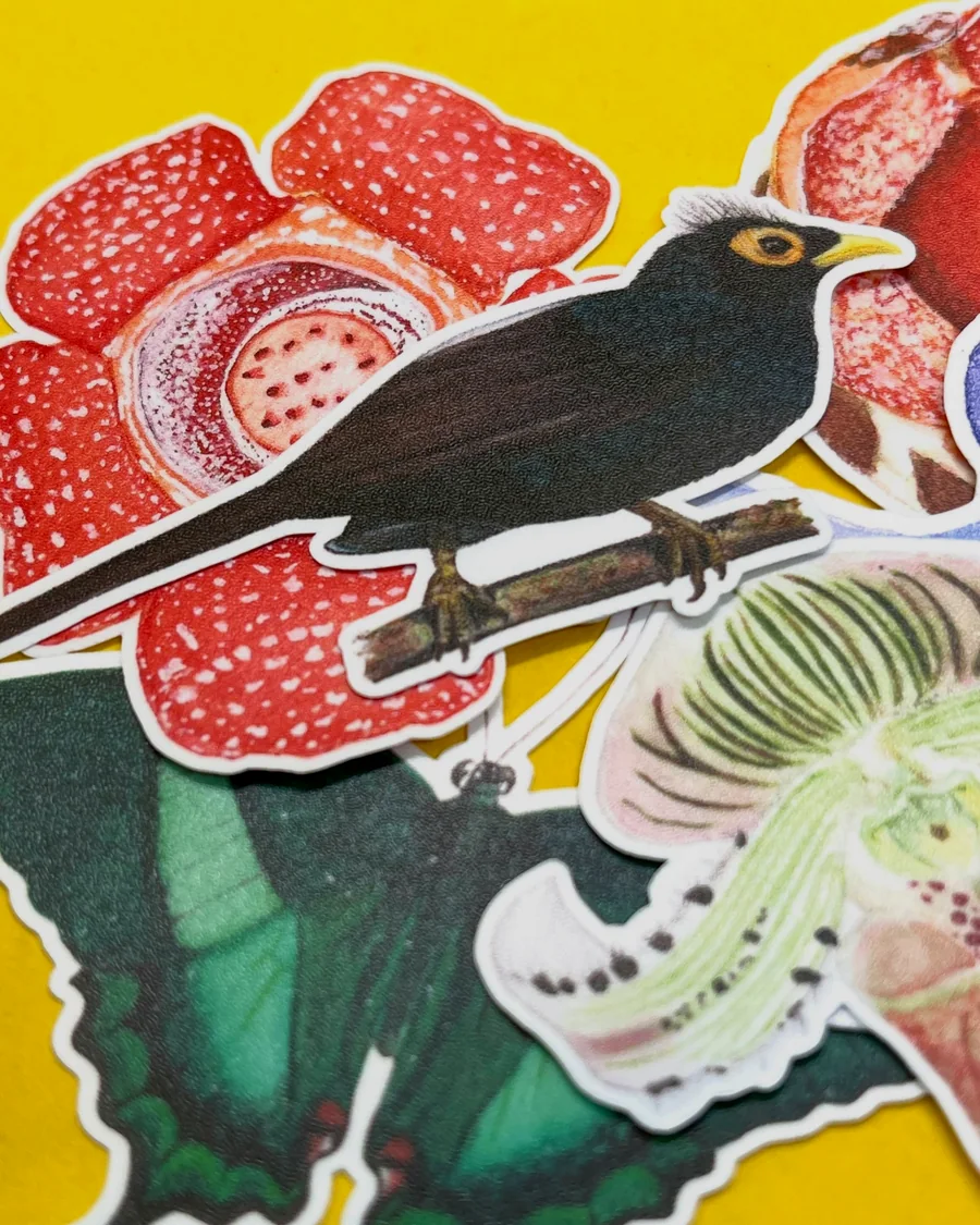 Close-up of die-cut stickers of a black bird and red flowers on yellow paper