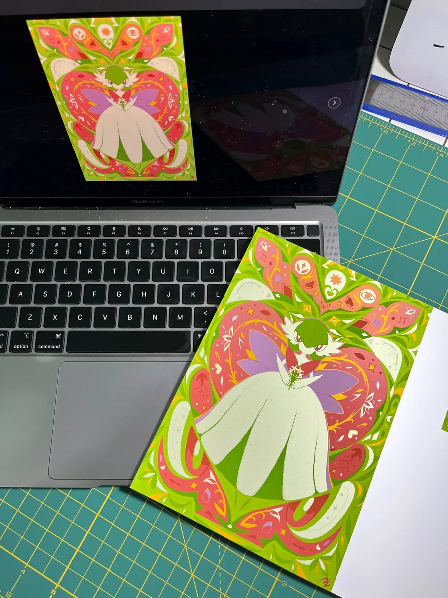 Green, pink and white illustrated art print lying next to a laptop that shows the original artwork on screen