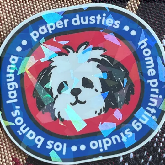 Round Paper Dusties sticker with a holo broken glass laminate over the artwork.