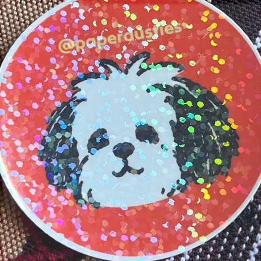 Round red Paper Dusties sticker with a sparkling holo dot laminate.
