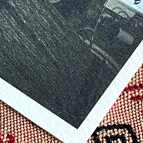 Corner of a photo printed on Recycled paper, showing its texture and white edge.