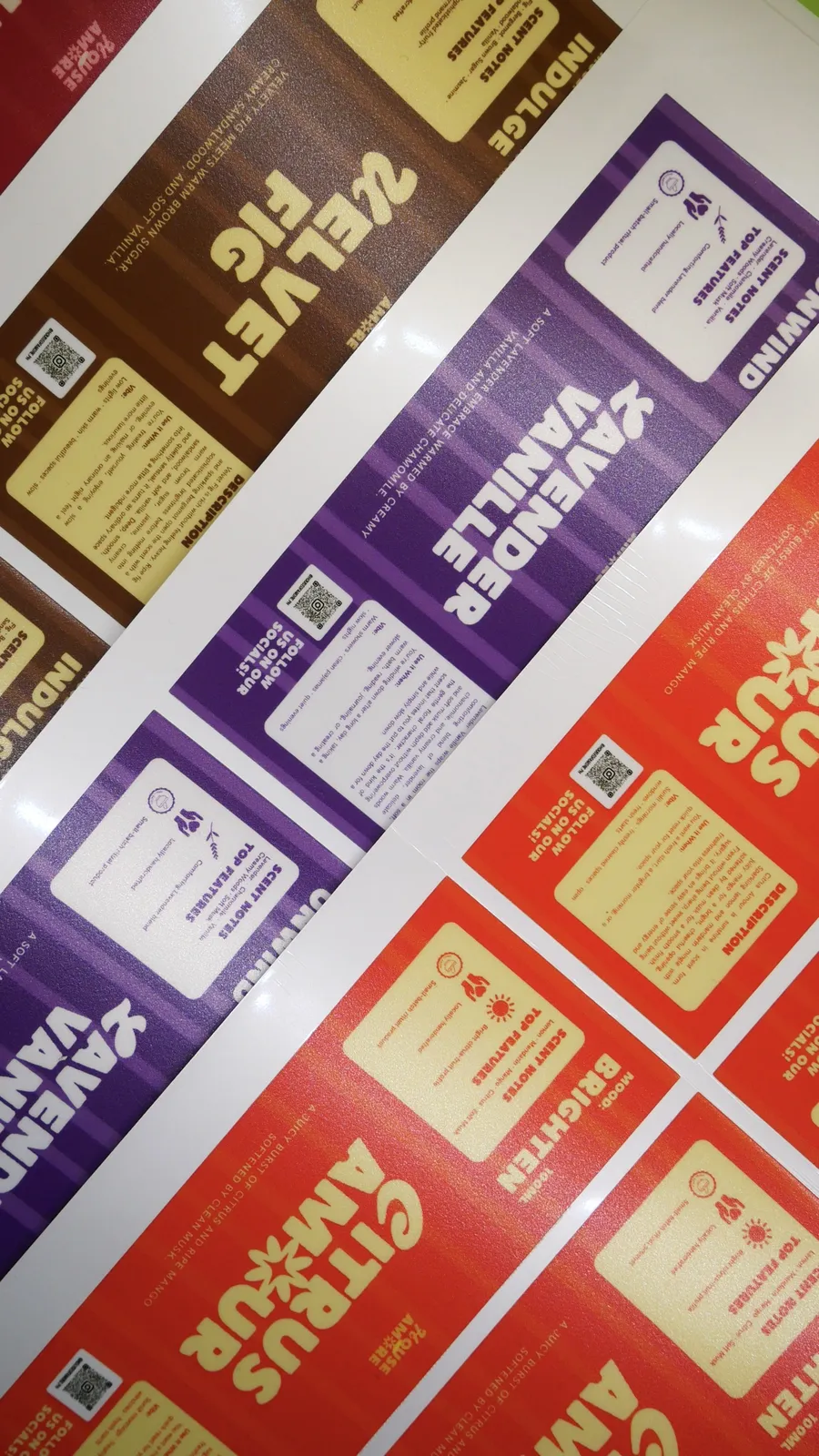 Sheets of printed product labels for scented candles in purple, red, and brown