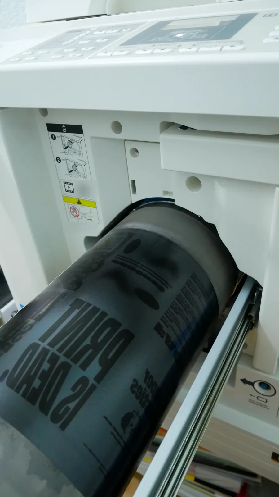 RISO printer with the print cylinder pulled out, a master with bold PRINT IS DEAD lettering wrapped around the drum
