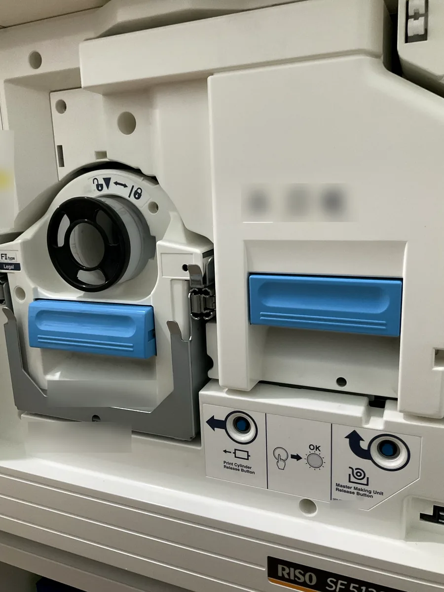 Front of a RISO SF5130 showing the ink cartridge slot, the master making unit, and the blue release handles